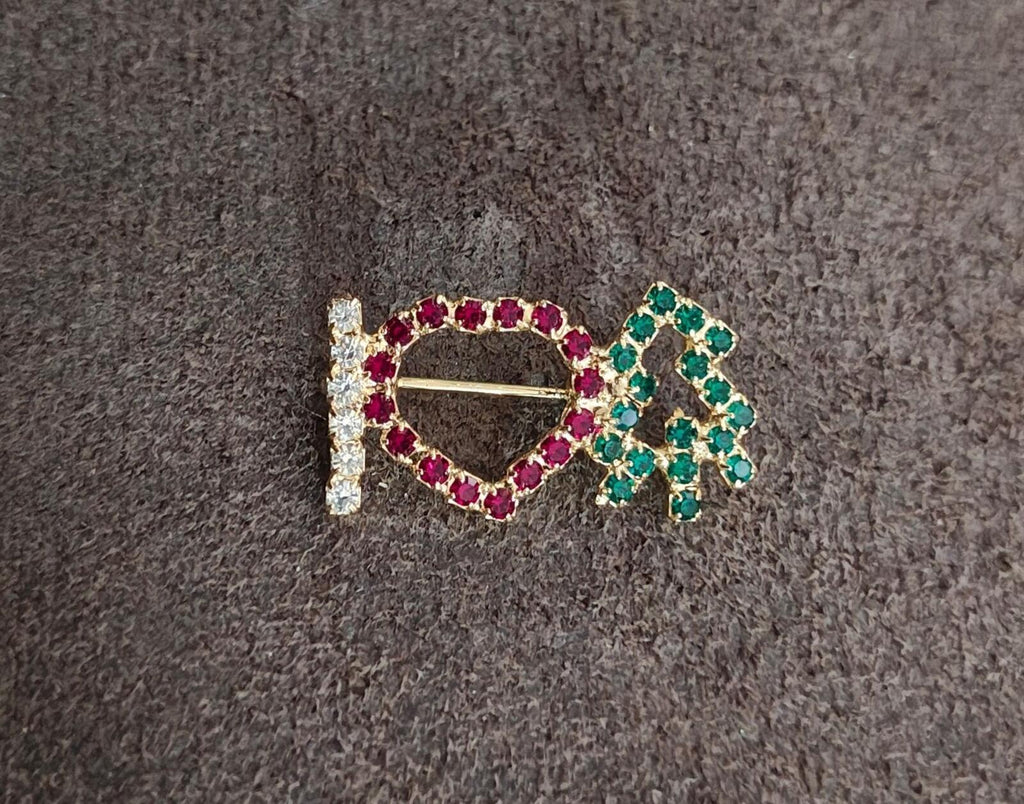 Rhinestone brooch on dark fabric: red heart outline with clear stones and green tree