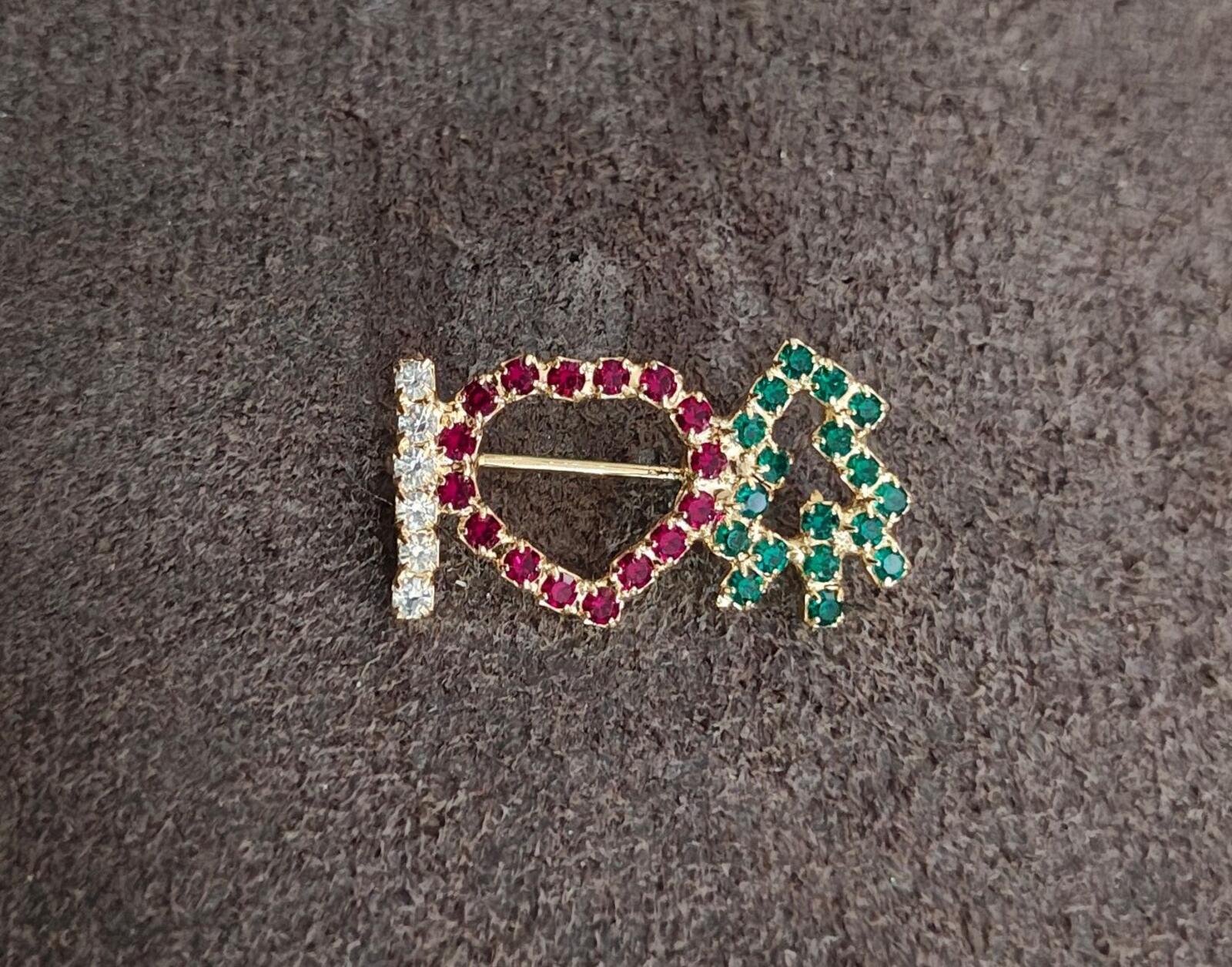 Rhinestone brooch on dark fabric: red heart outline with clear stones and green tree