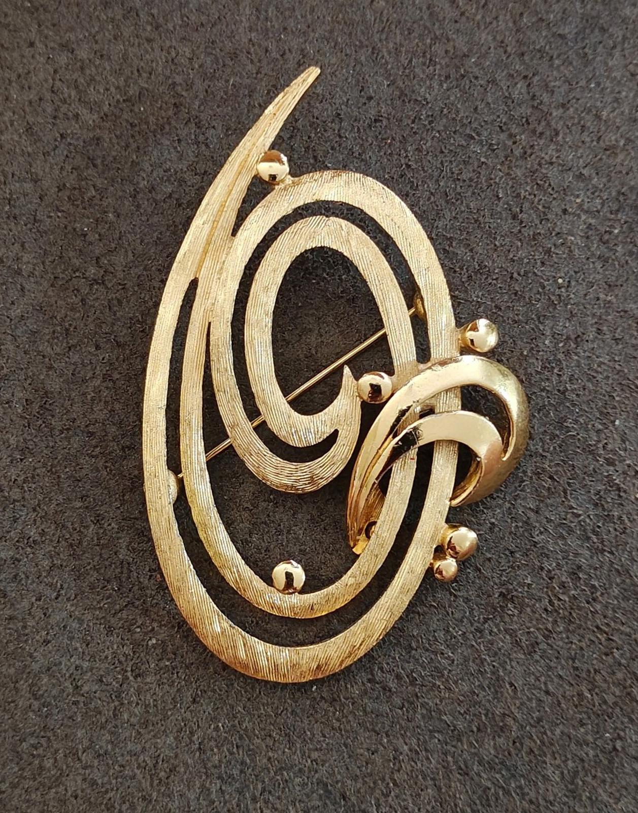 Gold tone oval brooch pin with double swirl design and round back fastener