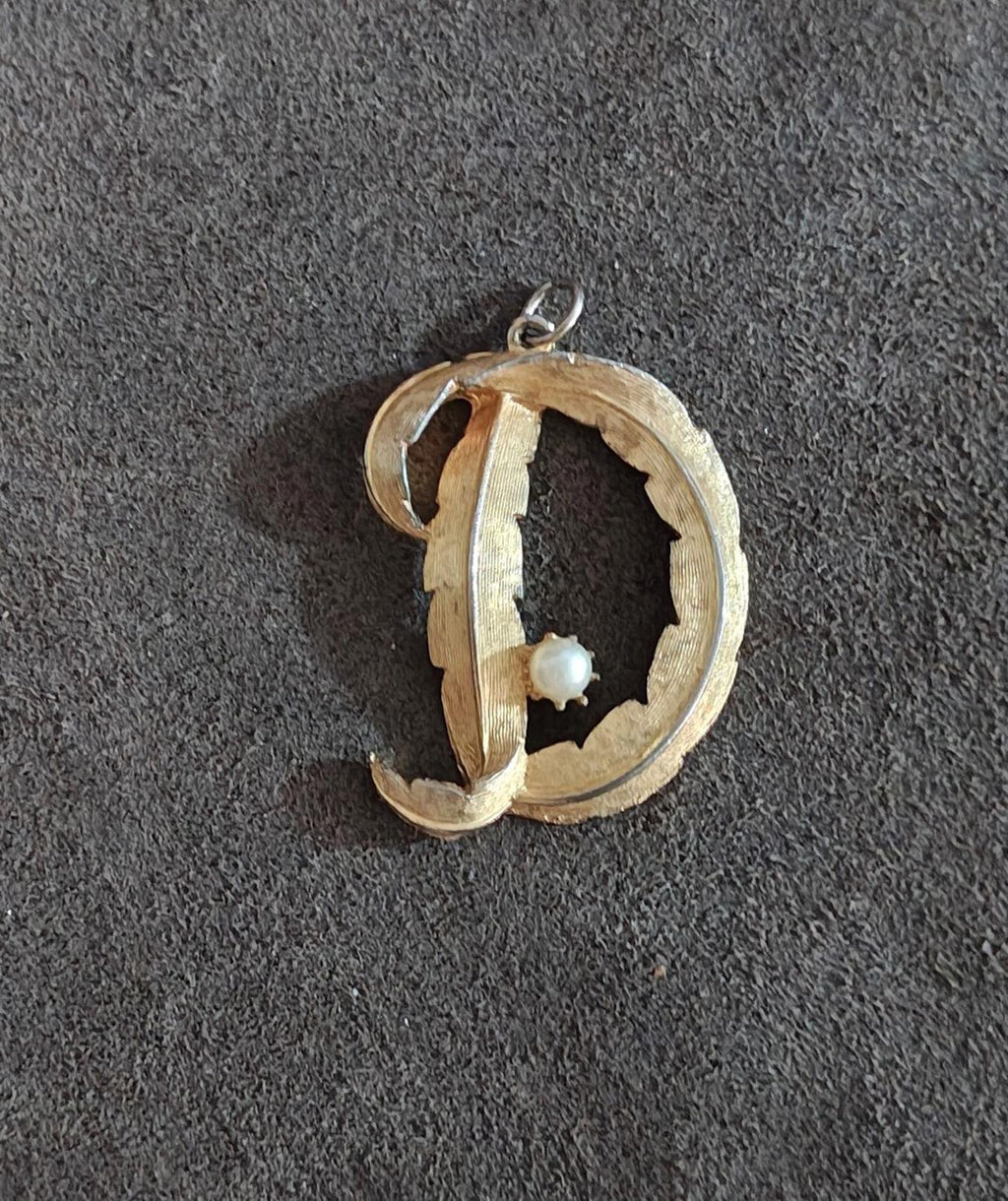 Gold-tone D monogram pendant with white pearl center and silver hanging bail