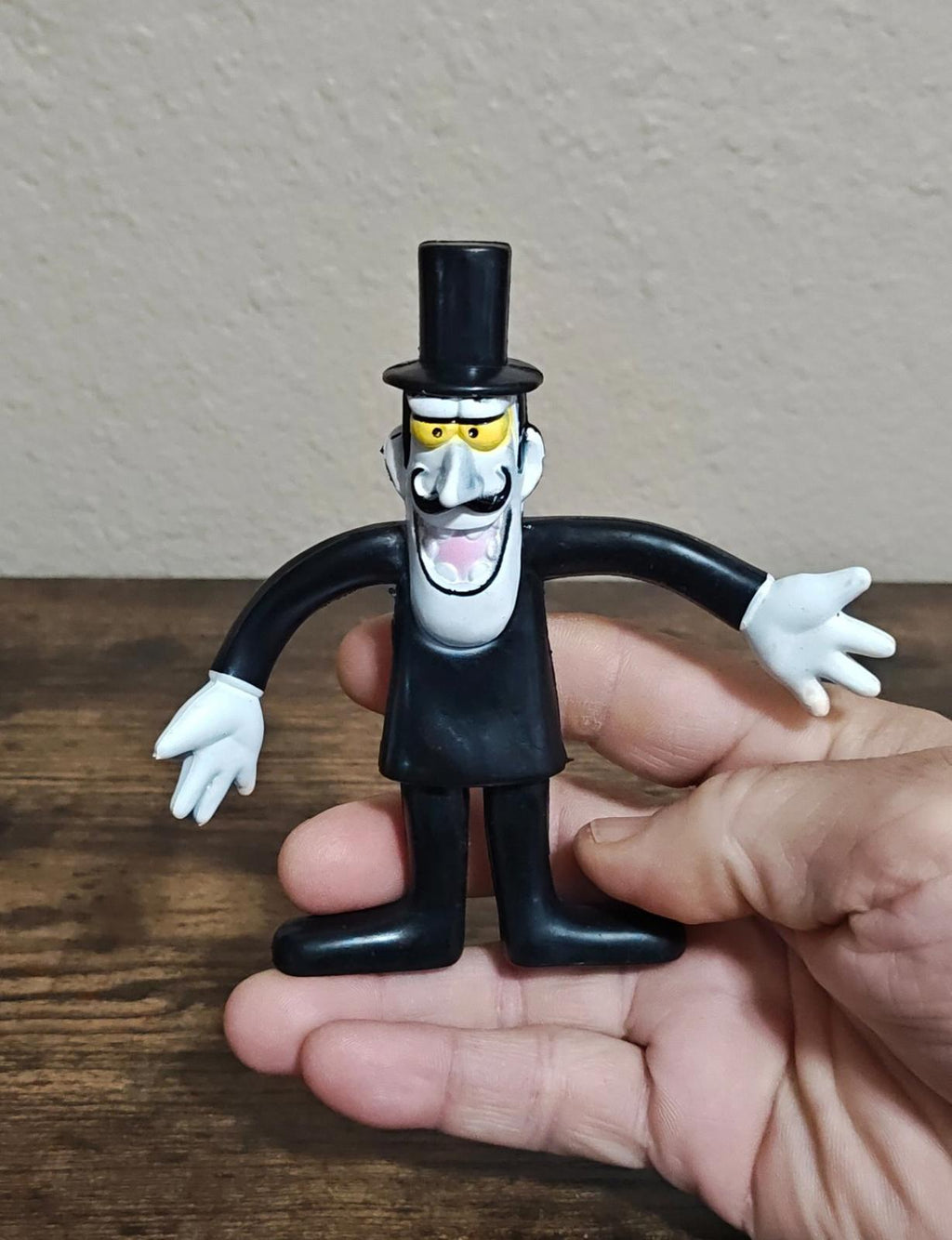 Black bendable collectible cartoon figure standing with arms out, white hands and top hat.