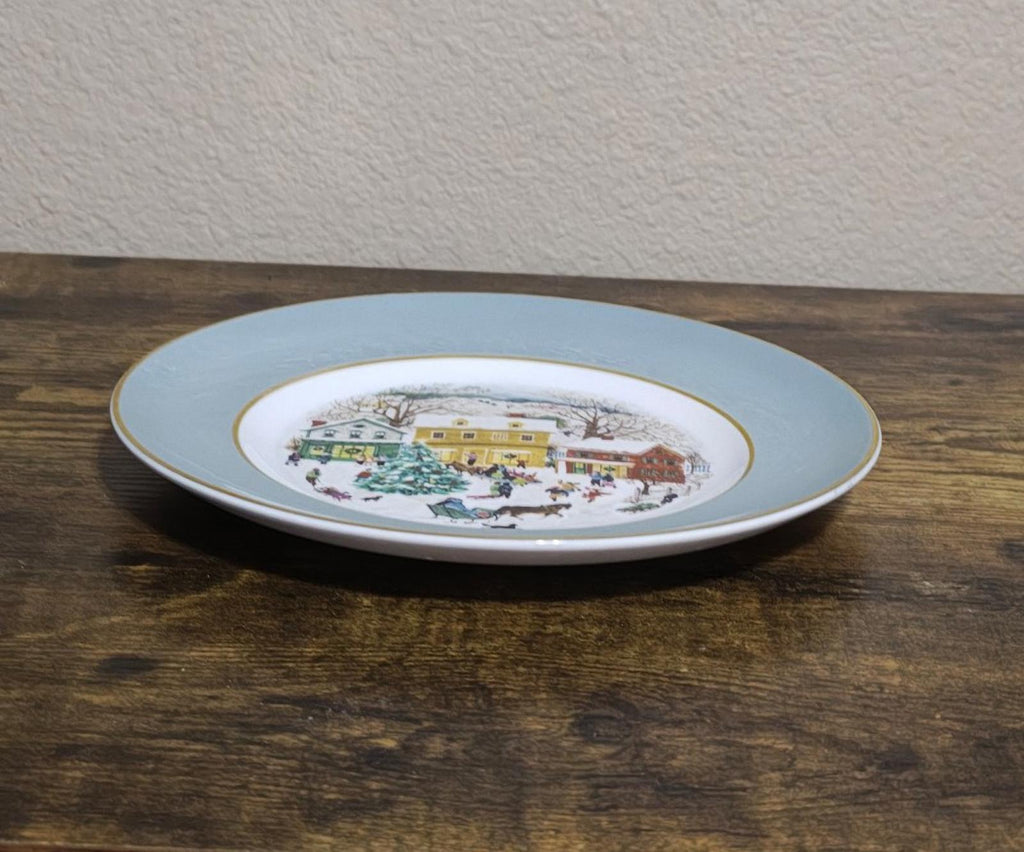 Light blue porcelain Christmas plate with 1980 village scene, viewed from side profile