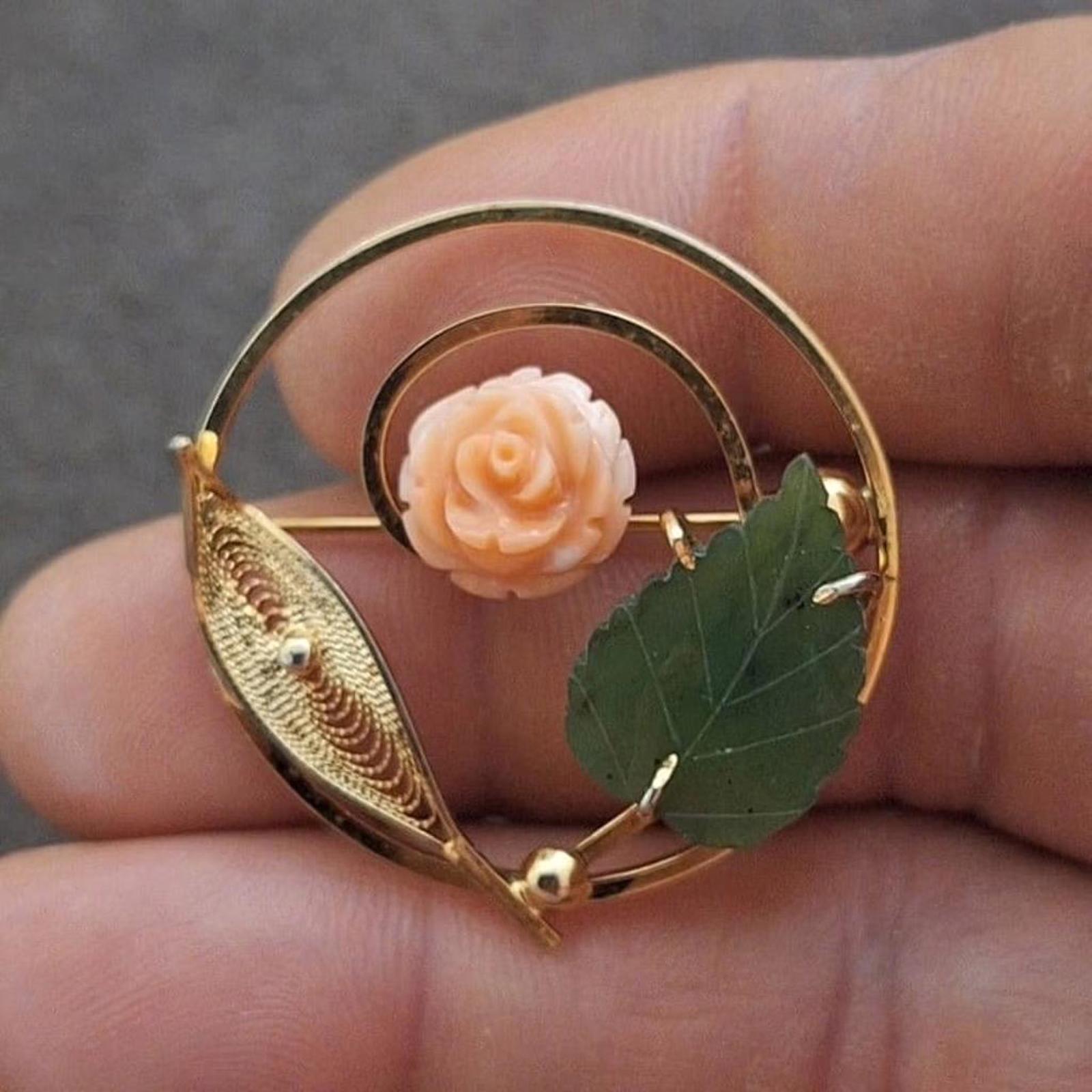 Gold-tone filigree brooch with pale rose cabochon and green leaf accents.