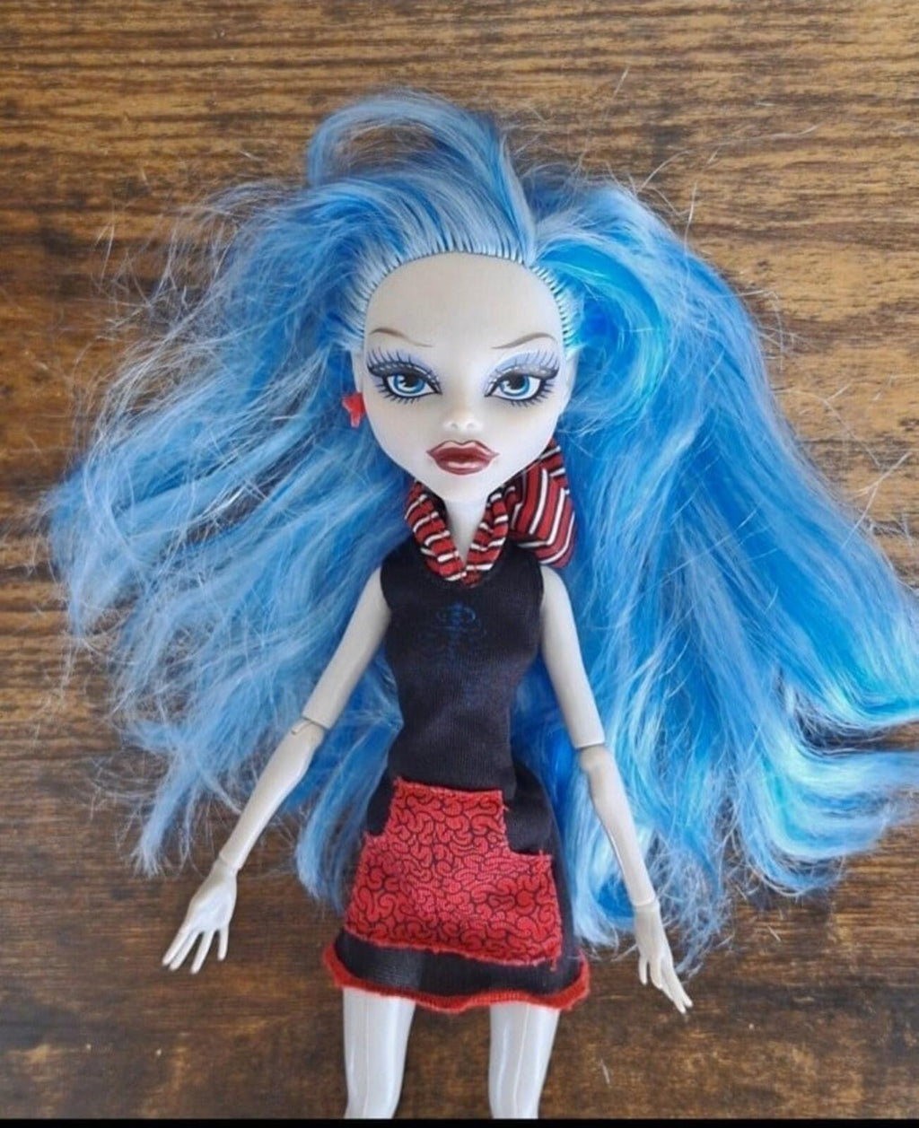 Monster doll close-up with light-blue hair, black dress and red textured skirt, striped collar