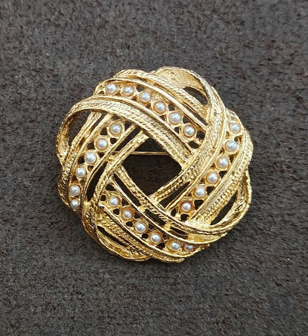 Gold-tone brooch with faux pearl border and swirling filigree crosshatch design