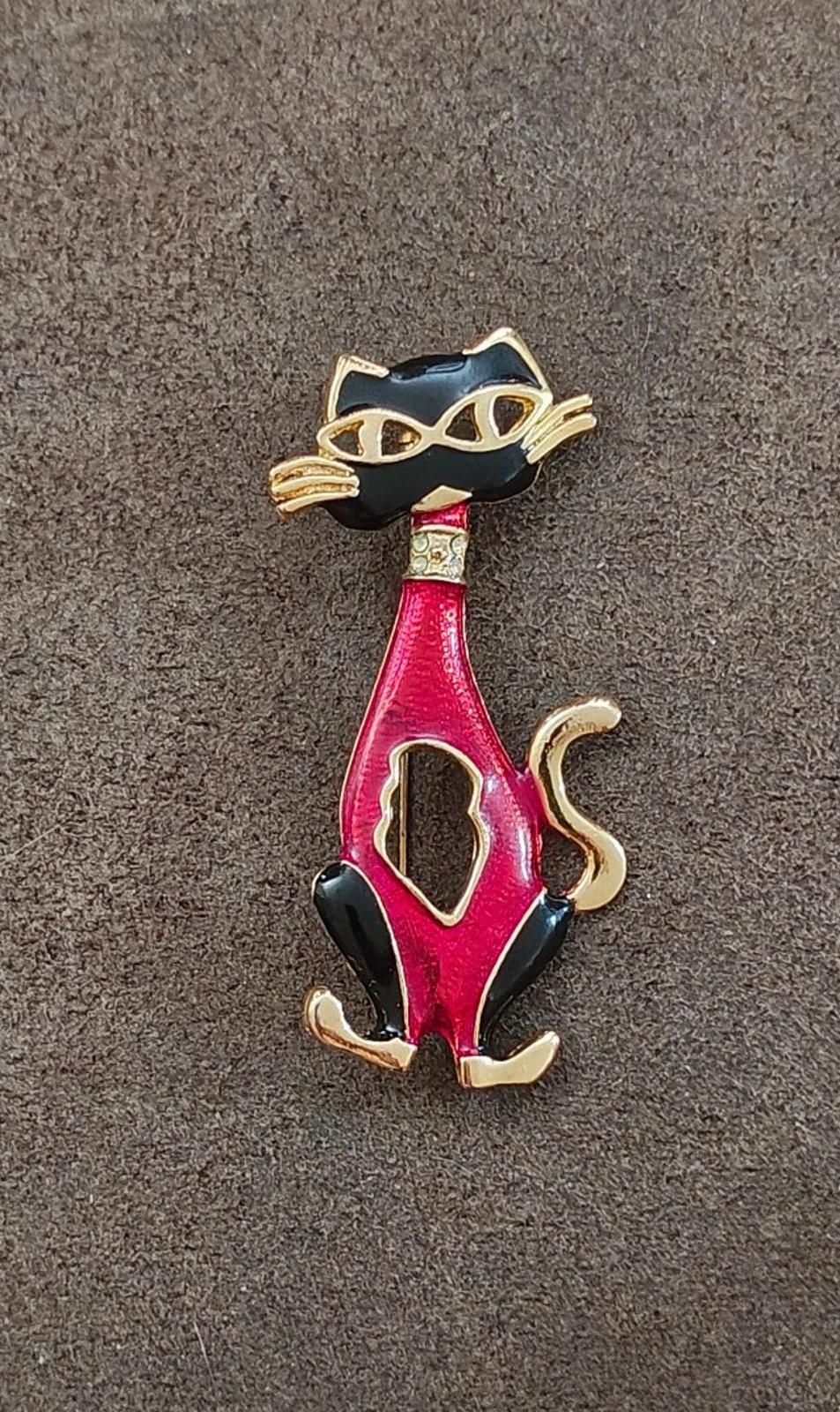 Red and black enamel cat mask brooch with gold-tone detailing, small standing cat.