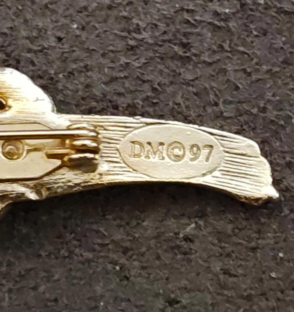 Gold tone brooch back plate stamped DM97, close-up