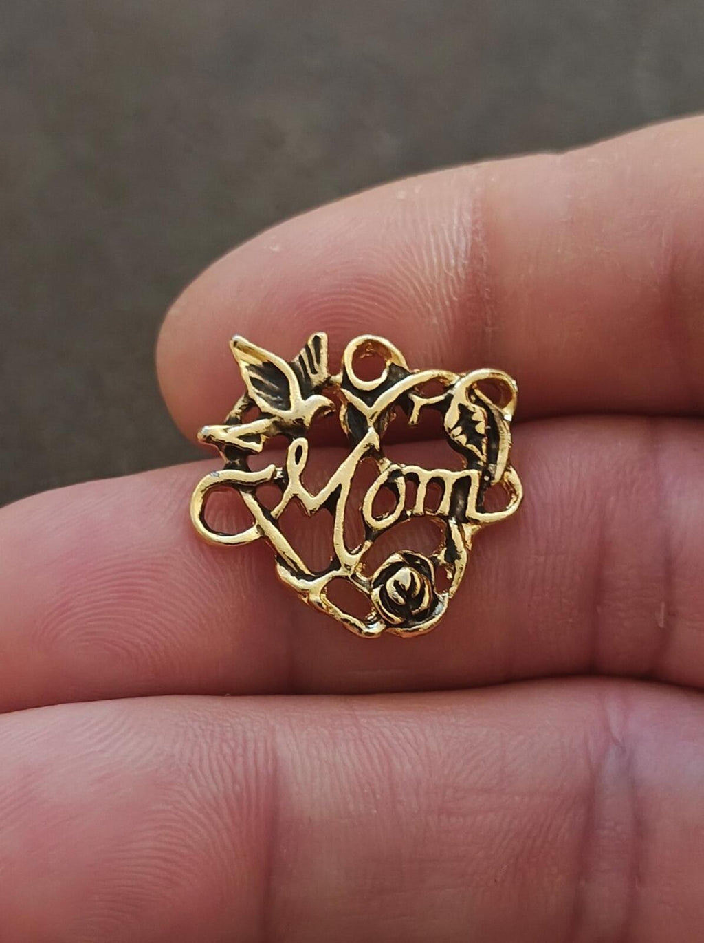 Gold-tone floral heart pin with rose and “Mom” charm text on dark backing