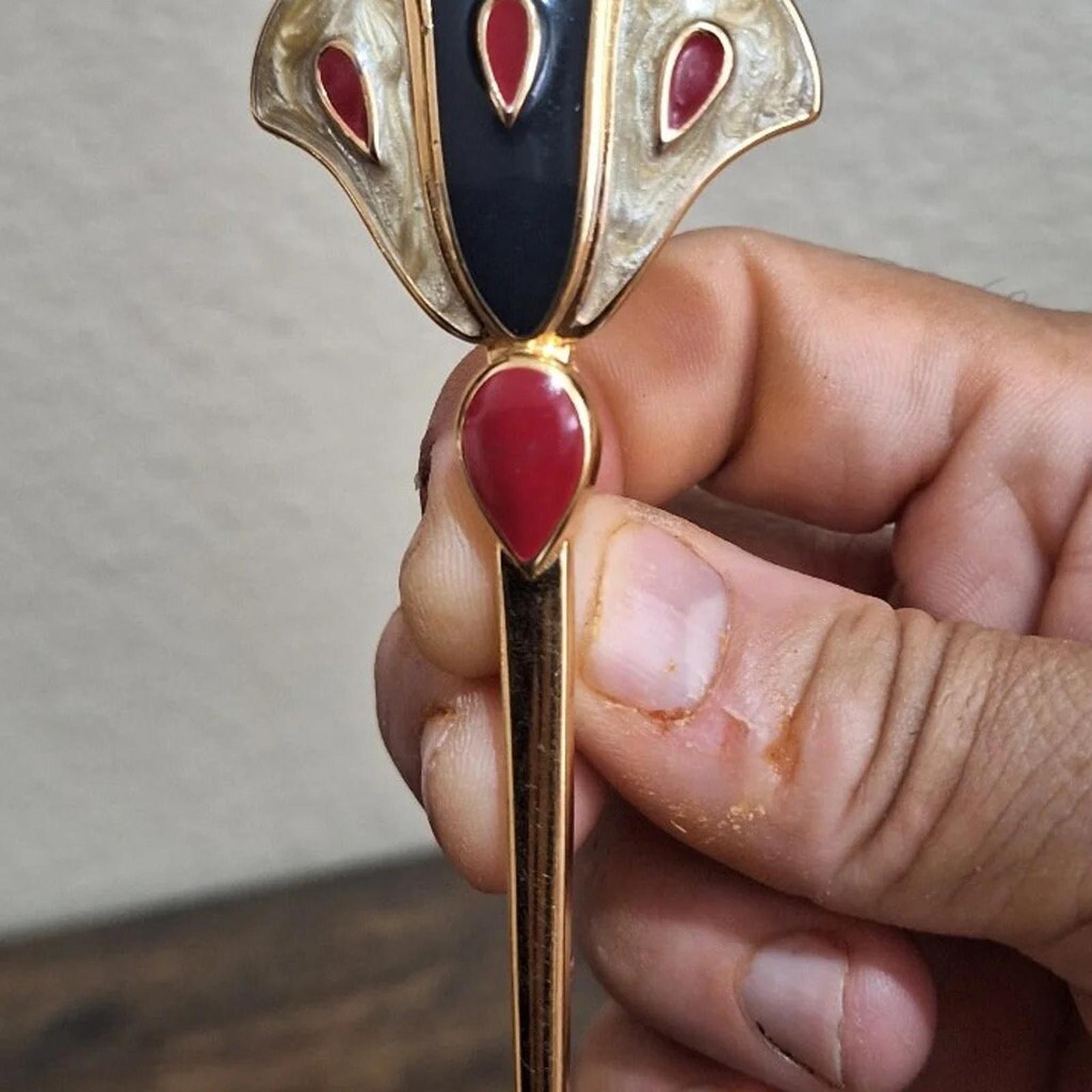 Hand holding Monet gold-tone enamel flower pin brooch with dark blue center and red petals