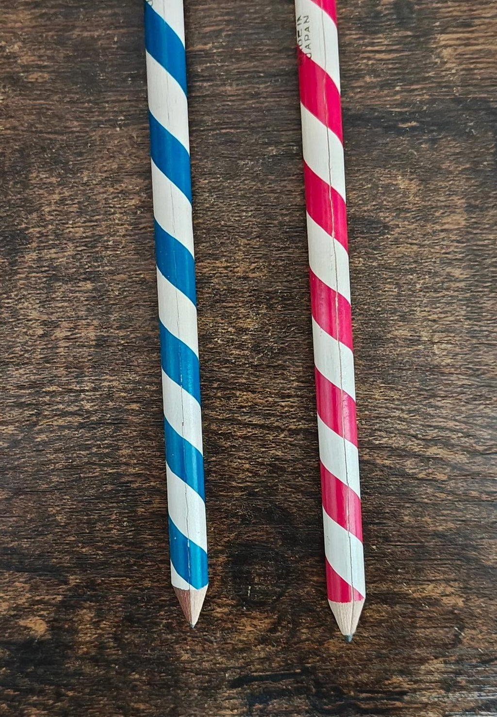 Decorative pencil shafts with blue-and-white and red-and-white diagonal stripes and pointed tips.