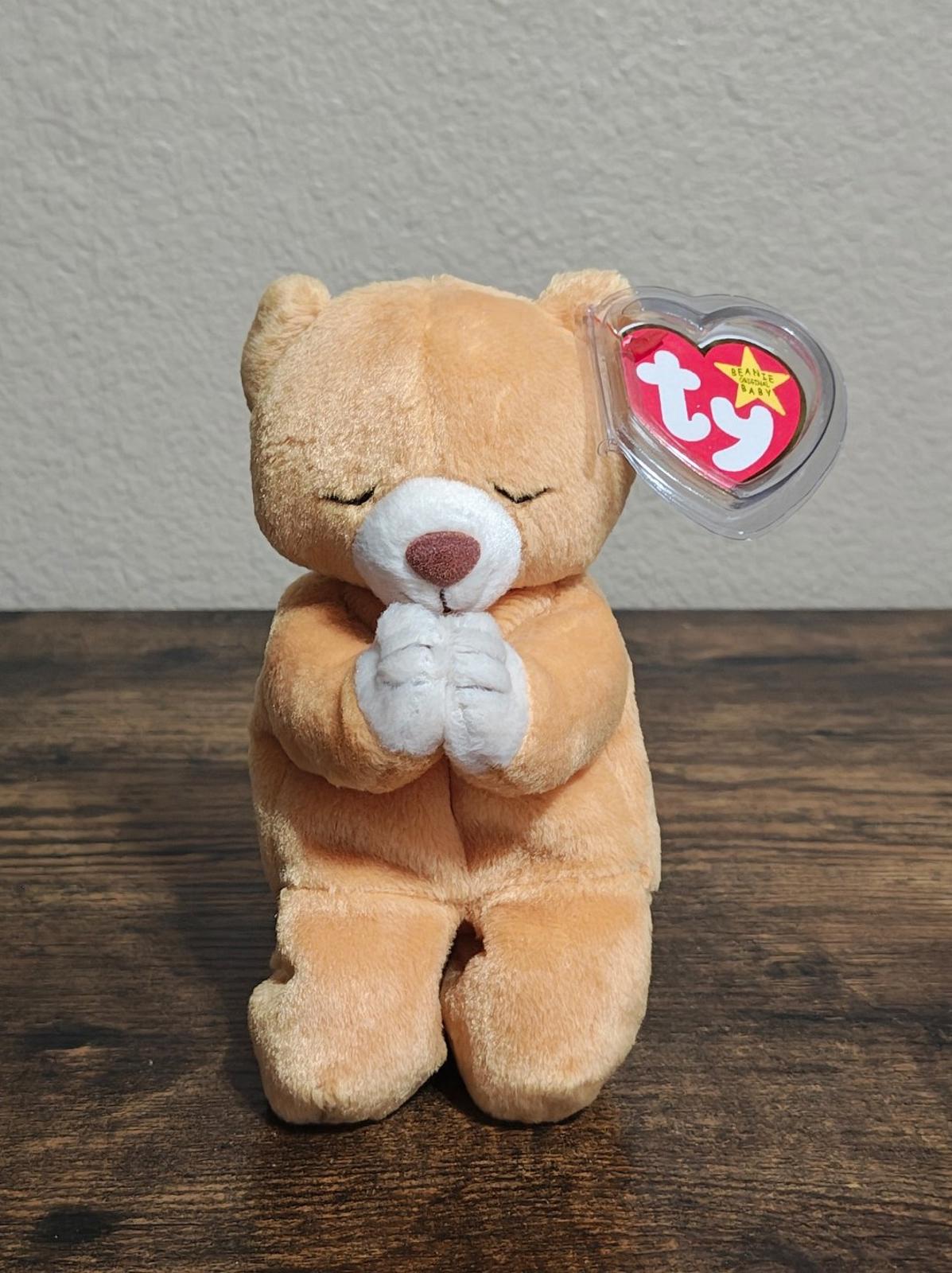 Standing brown plush bear with white praying hands and clear Ty heart tag