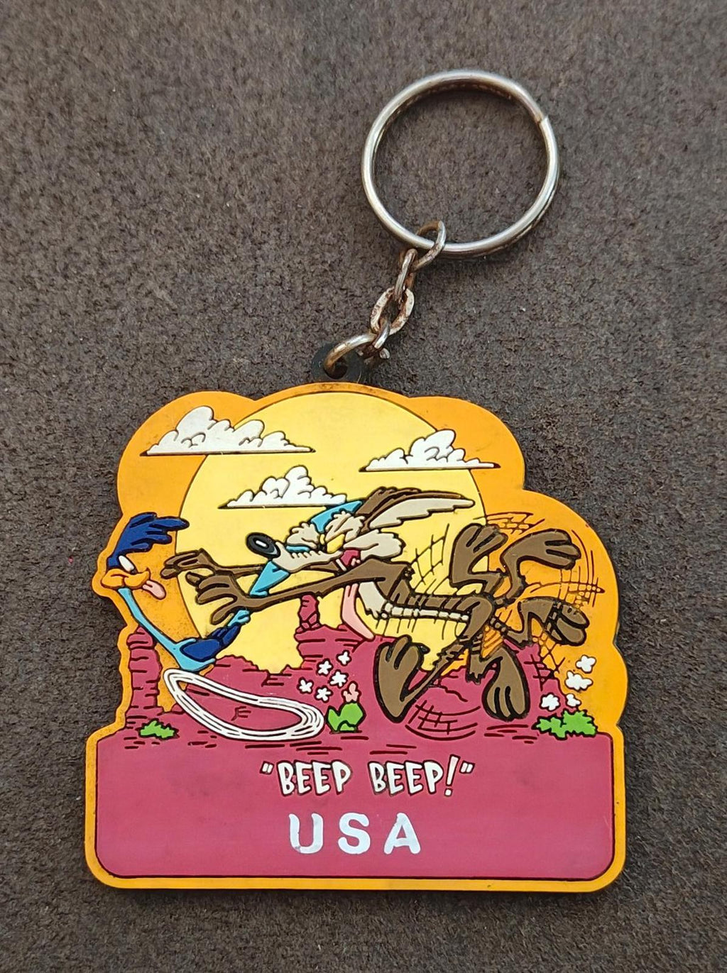 Yellow and pink cartoon keychain featuring Road Runner vs Wile E. Coyote, metal ring.