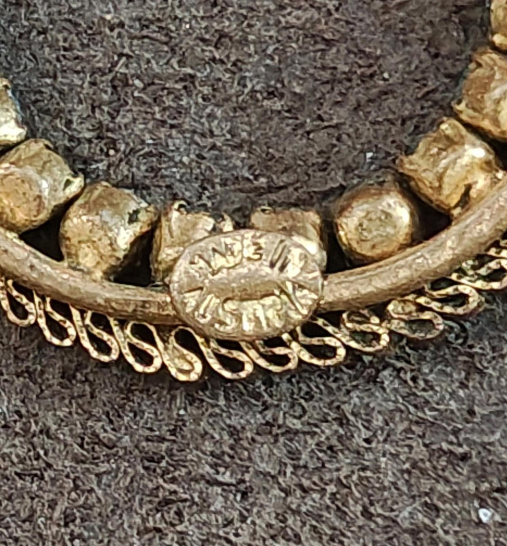 Close-up of gold-tone clasp with engraved details and blue stone settings