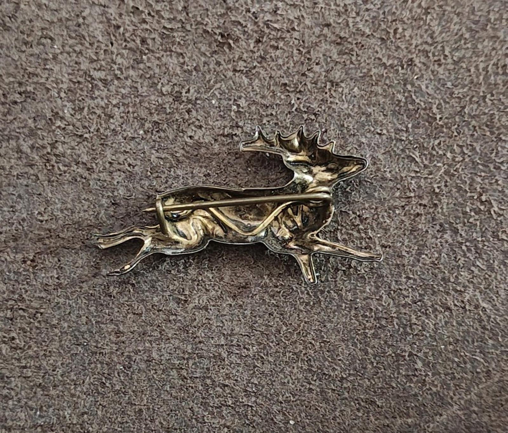 Brass deer figurine with arched antlers, running pose on textured gray surface