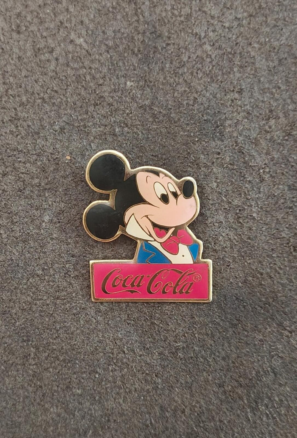 Gold-tone enamel Mickey Mouse Coca-Cola sign pin, small front view on carpet