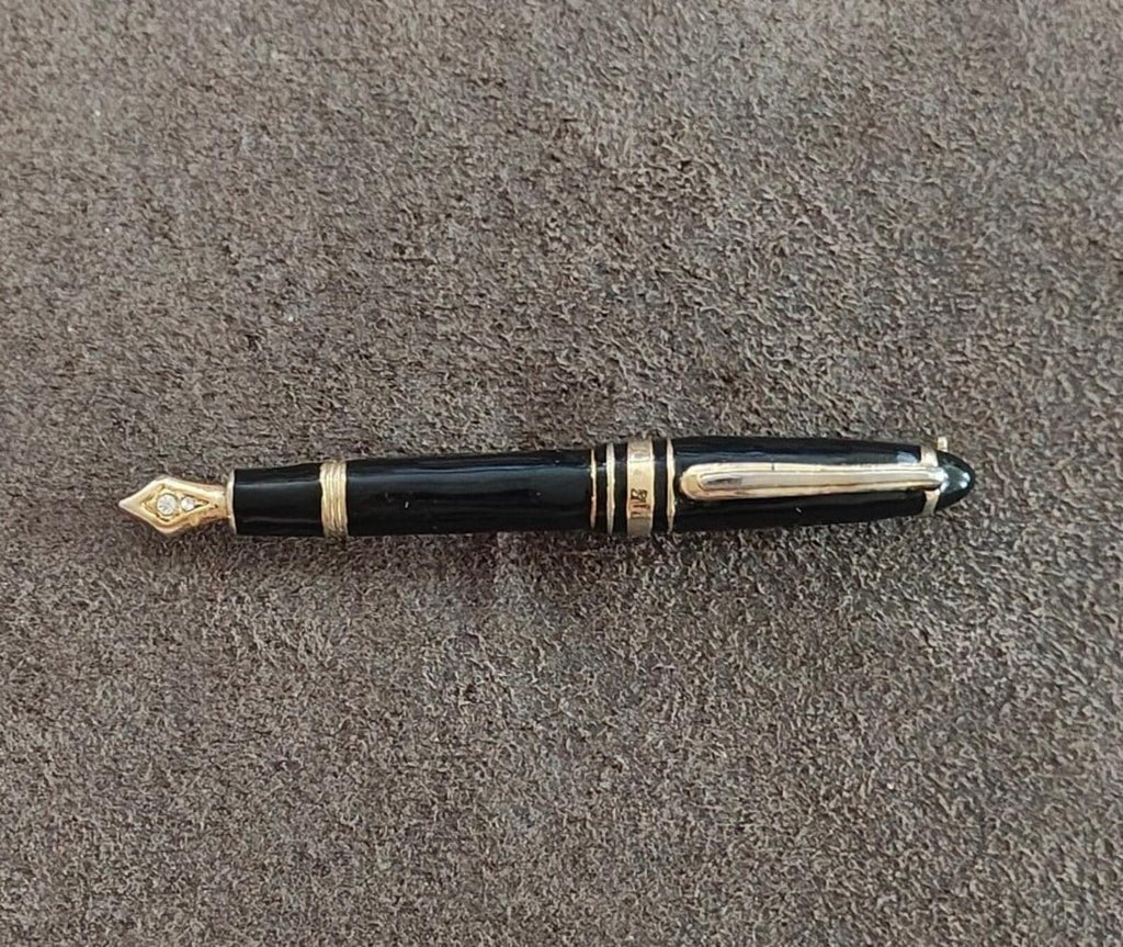 Black enamel fountain pen brooch with gold-tone bands and a clear rhinestone tip.