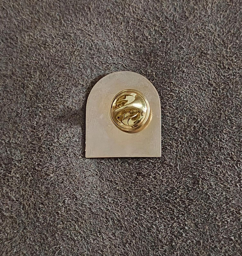 Back of gold-tone enamel crest pin with round clasp