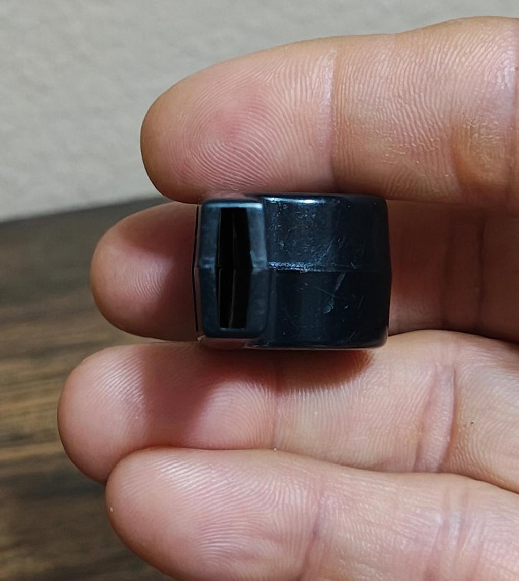 Black whistle end cap with rectangular slot, side angle held by fingers.
