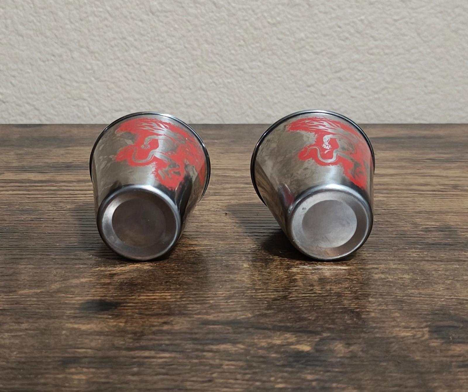 Bottom view of 2 stainless steel shot glasses with red dragon print on exterior