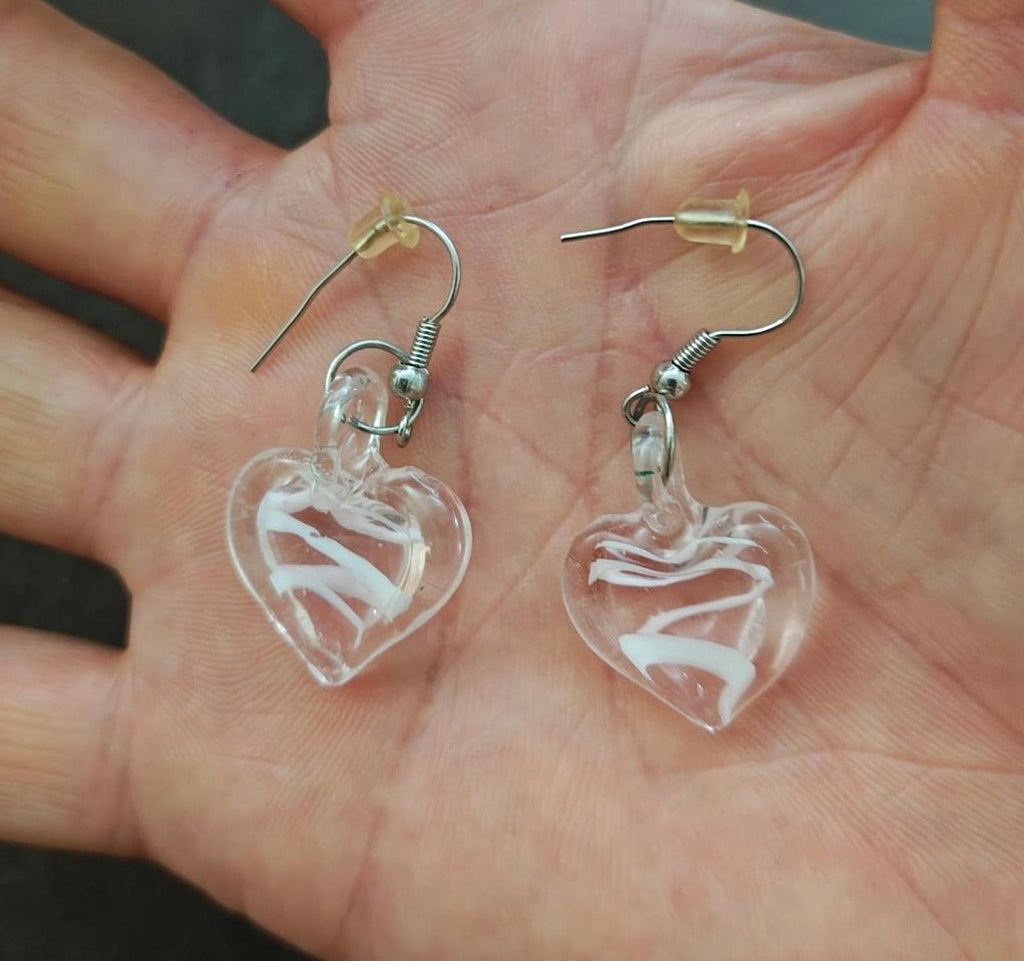 Two heart-shaped glass earrings with swirl inlays and silver-tone fishhook backs.