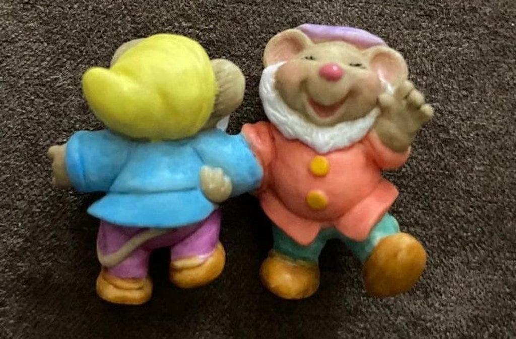 Two dwarf figurines in yellow-blue and orange outfits, standing back-to-camera view.