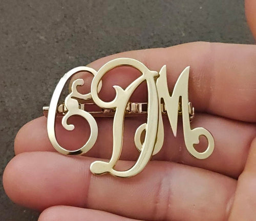 Gold-tone monogram brooch pin with red enamel letters E, D, M and decorative script