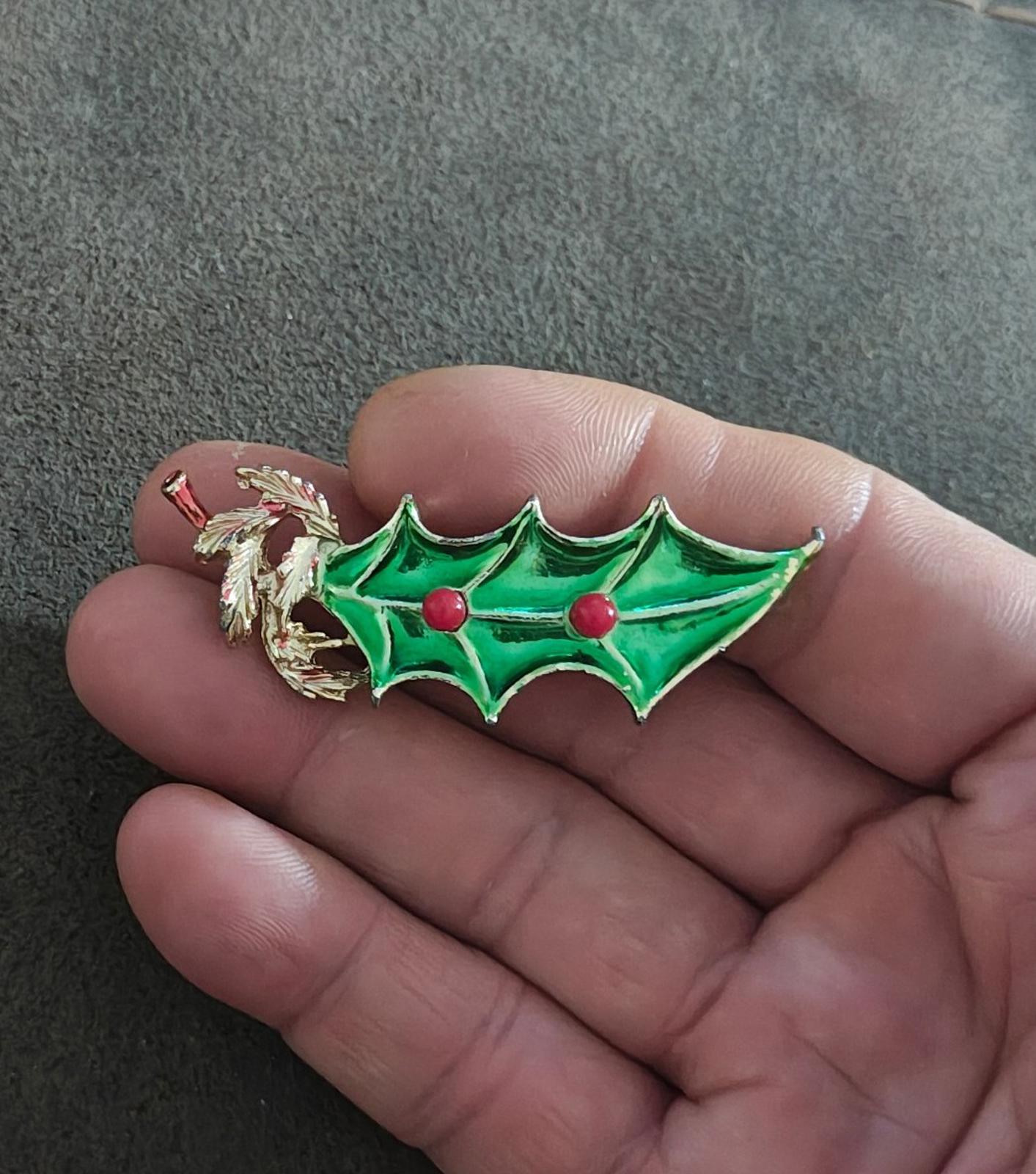 Green holly Christmas brooch with gold tone metal edges and red berry accents.