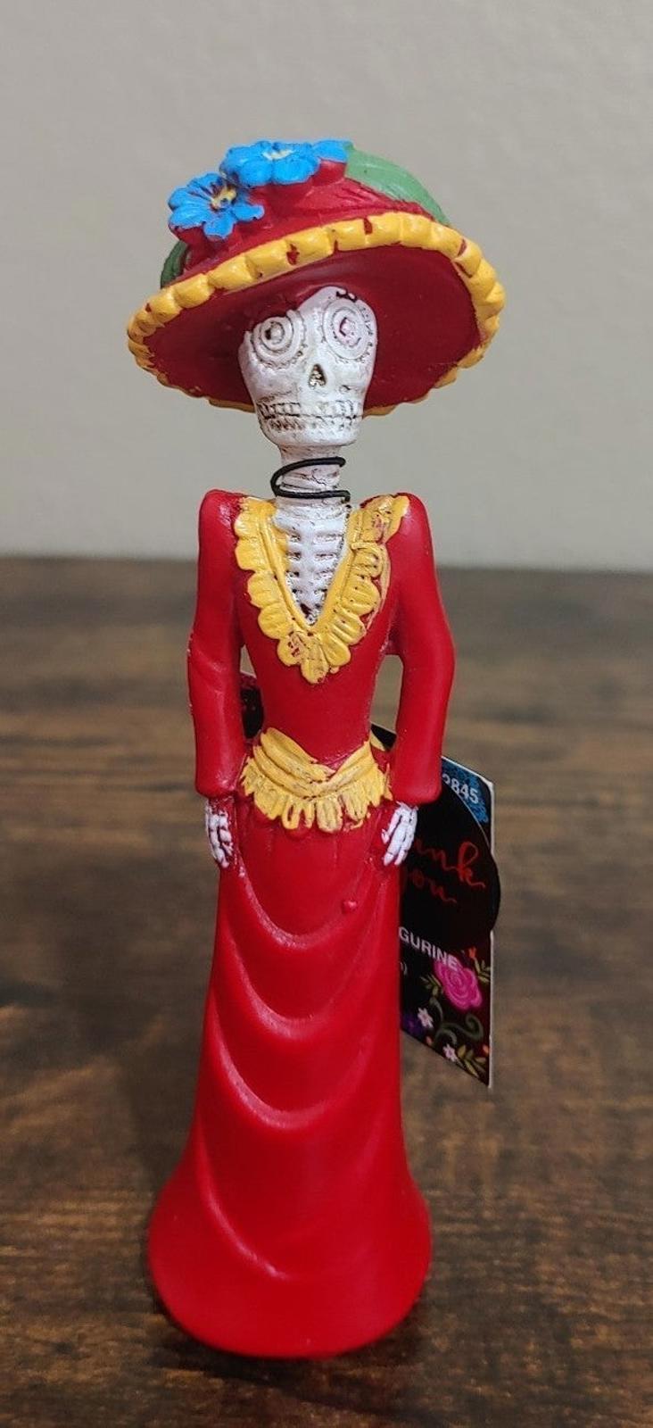 Day of the Dead lady figurine with sugar skull face, red dress and decorated sombrero