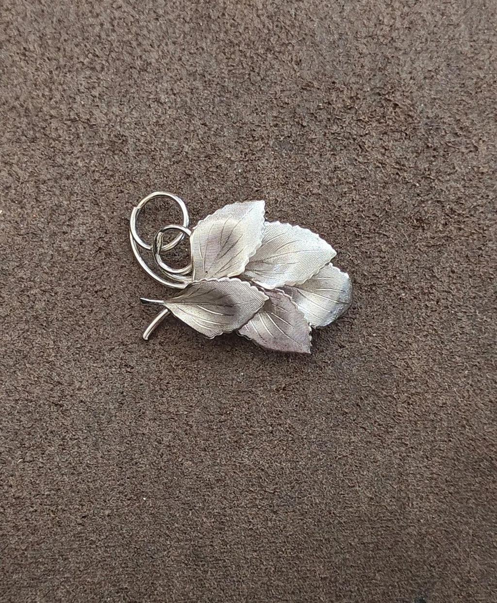 Silver leaf cluster brooch with textured veins and circular ring loop clasp