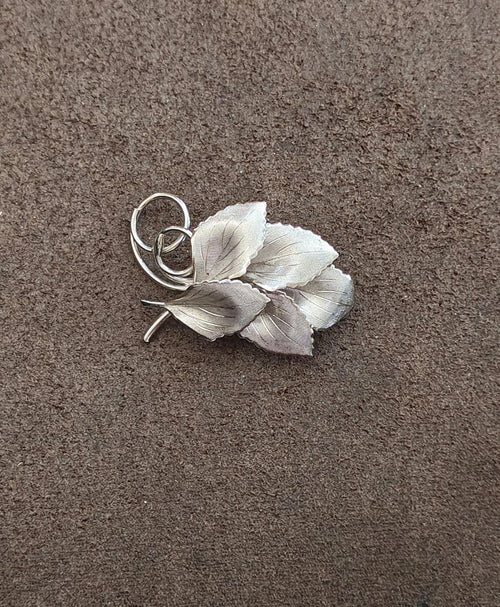 Silver leaf cluster brooch with textured veins and circular ring loop clasp