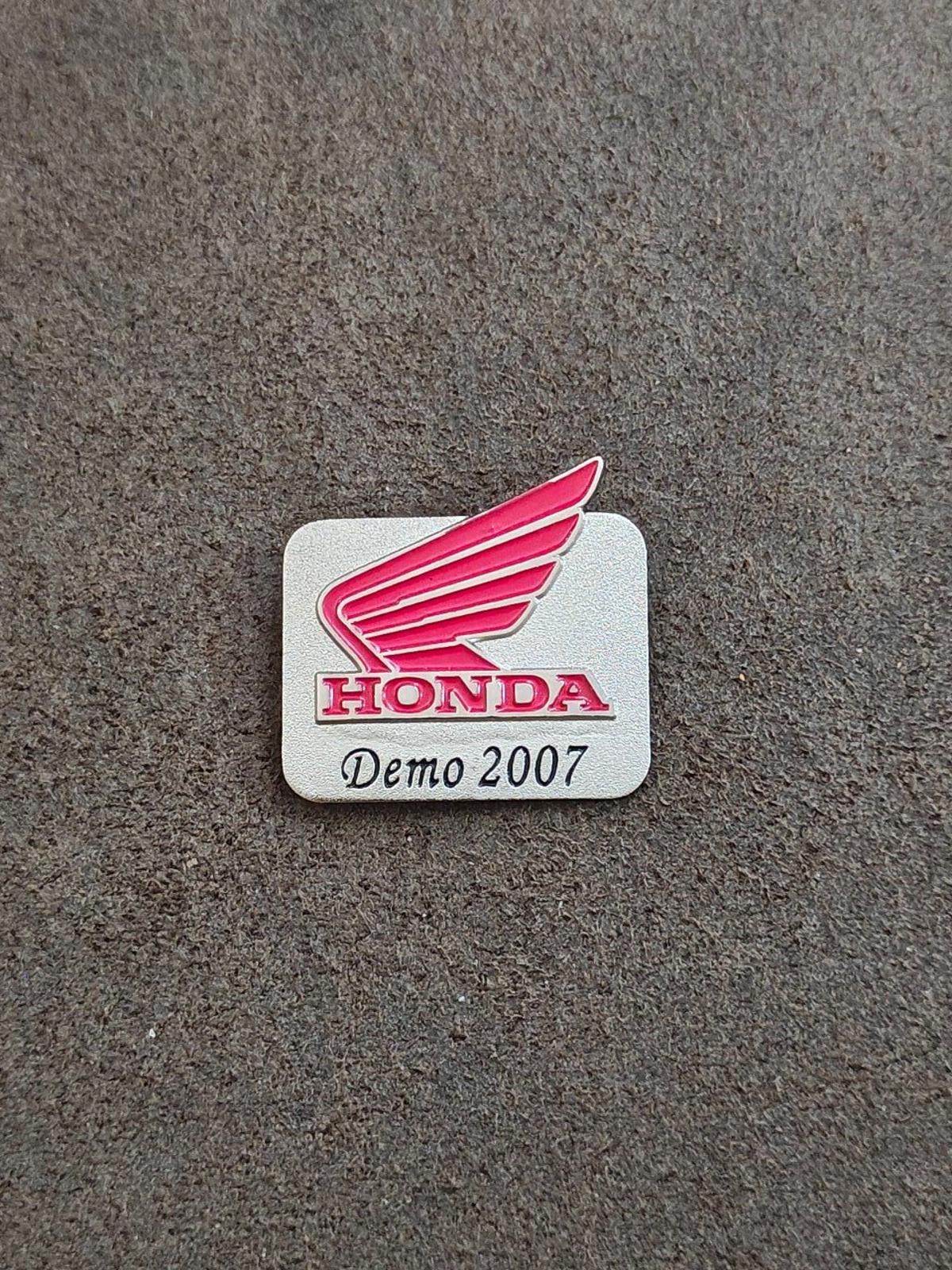 Silver-tone Honda Demo 2007 enamel pin on gray surface with red wings and HONDA