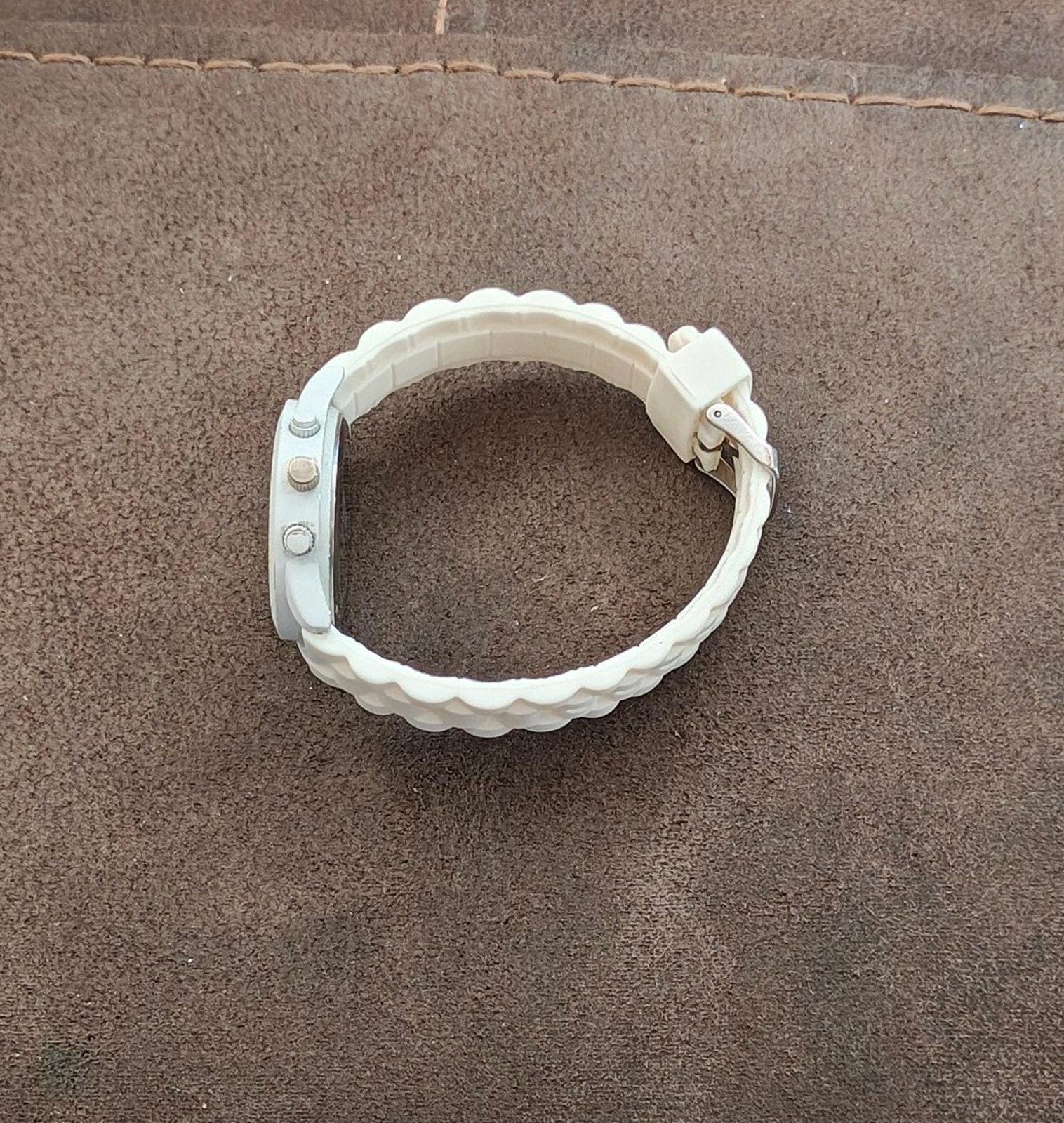 White silicone watch band close-up, circular watch case and strap loop with clasp