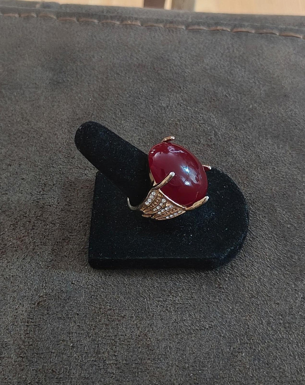 Red oval faux stone ring on black stand with gold-tone openwork shoulders