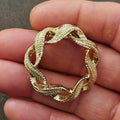 Gold-tone circular wreath brooch pin with leaf cutouts and warm red enamel accents