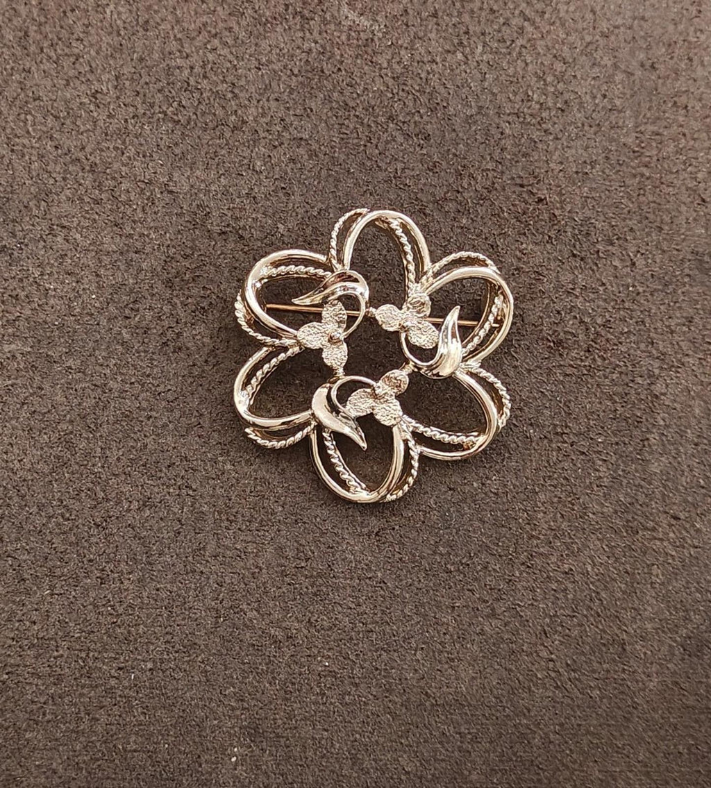 Gold-tone flower brooch with layered petals, curved loops, and a raised center