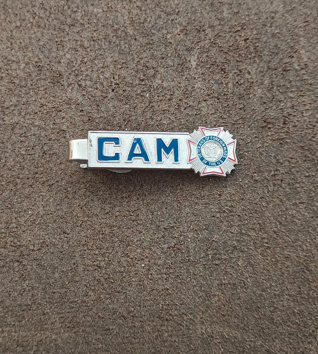 Silver-tone tie clip with blue “CAM” and circular emblem on end
