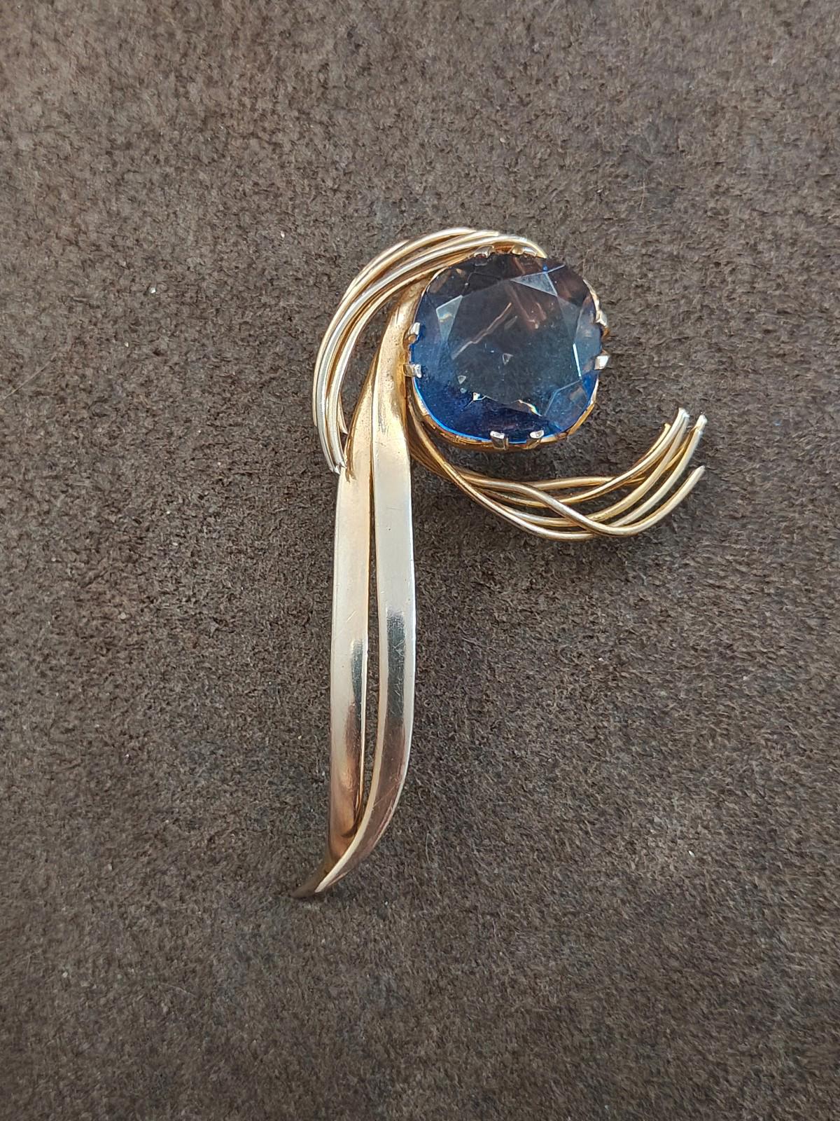 Gold-tone abstract brooch pin with large blue gemstone and curved swirls