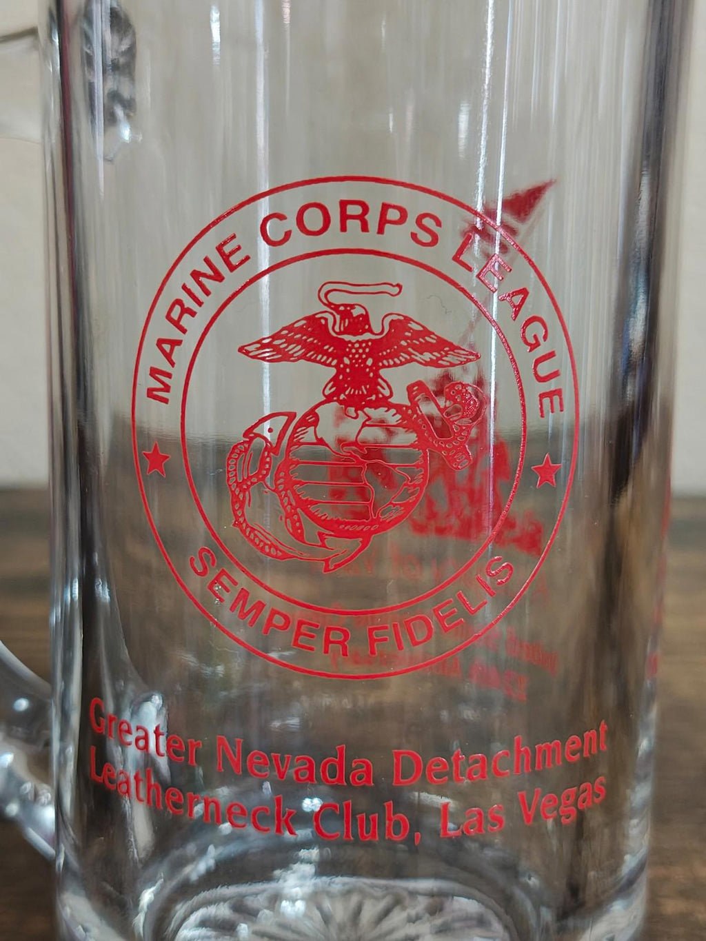 Clear beer mug close-up of red Marine Corps seal with club name text underneath