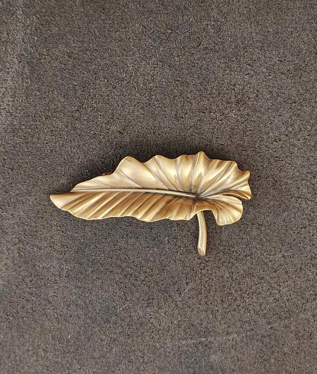 Gold-tone leaf brooch pin showing vertical pin stem and ridged leaf texture.