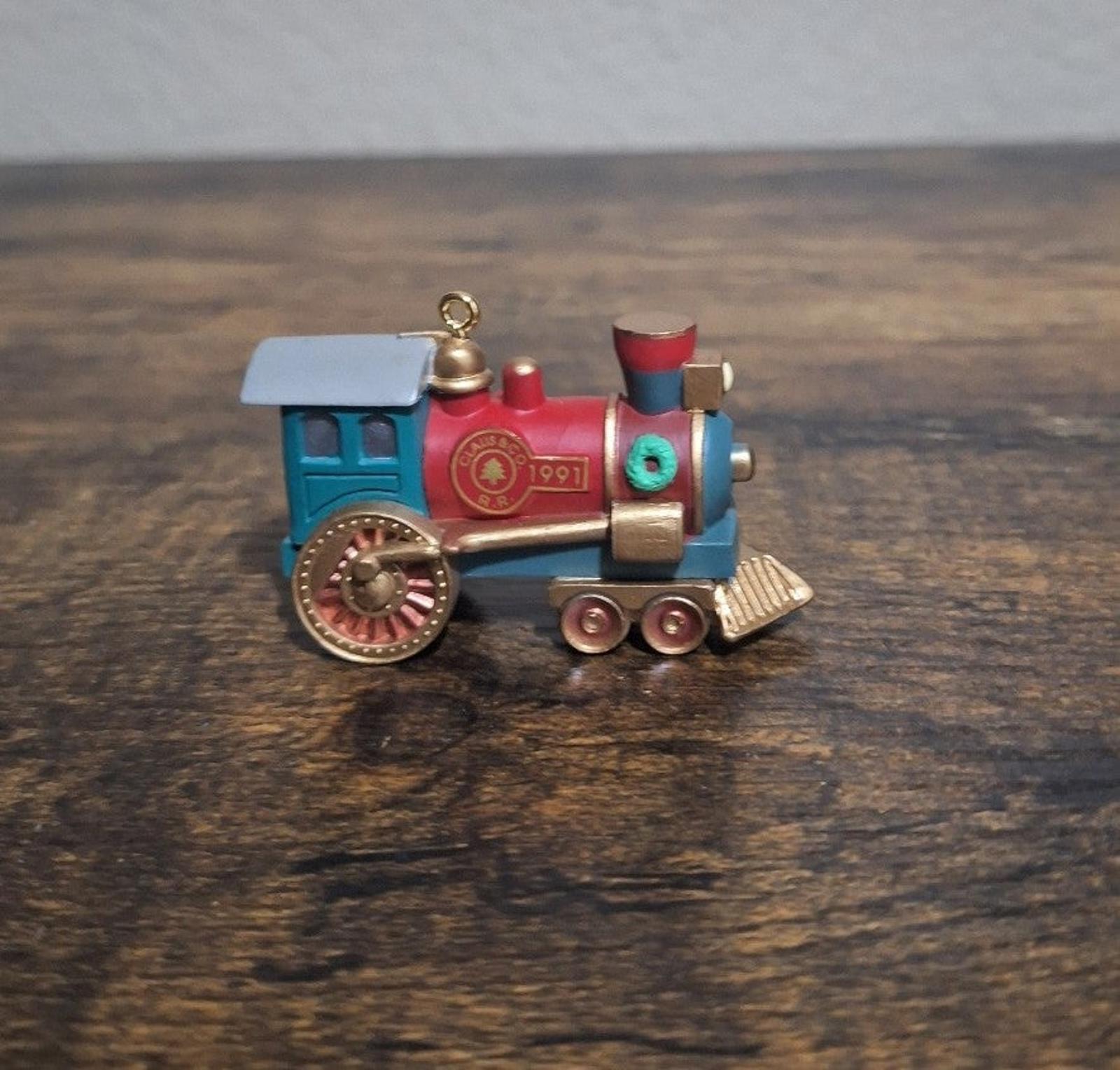 Blue and red train locomotive ornament, side view with large gold wheel and hanging loop