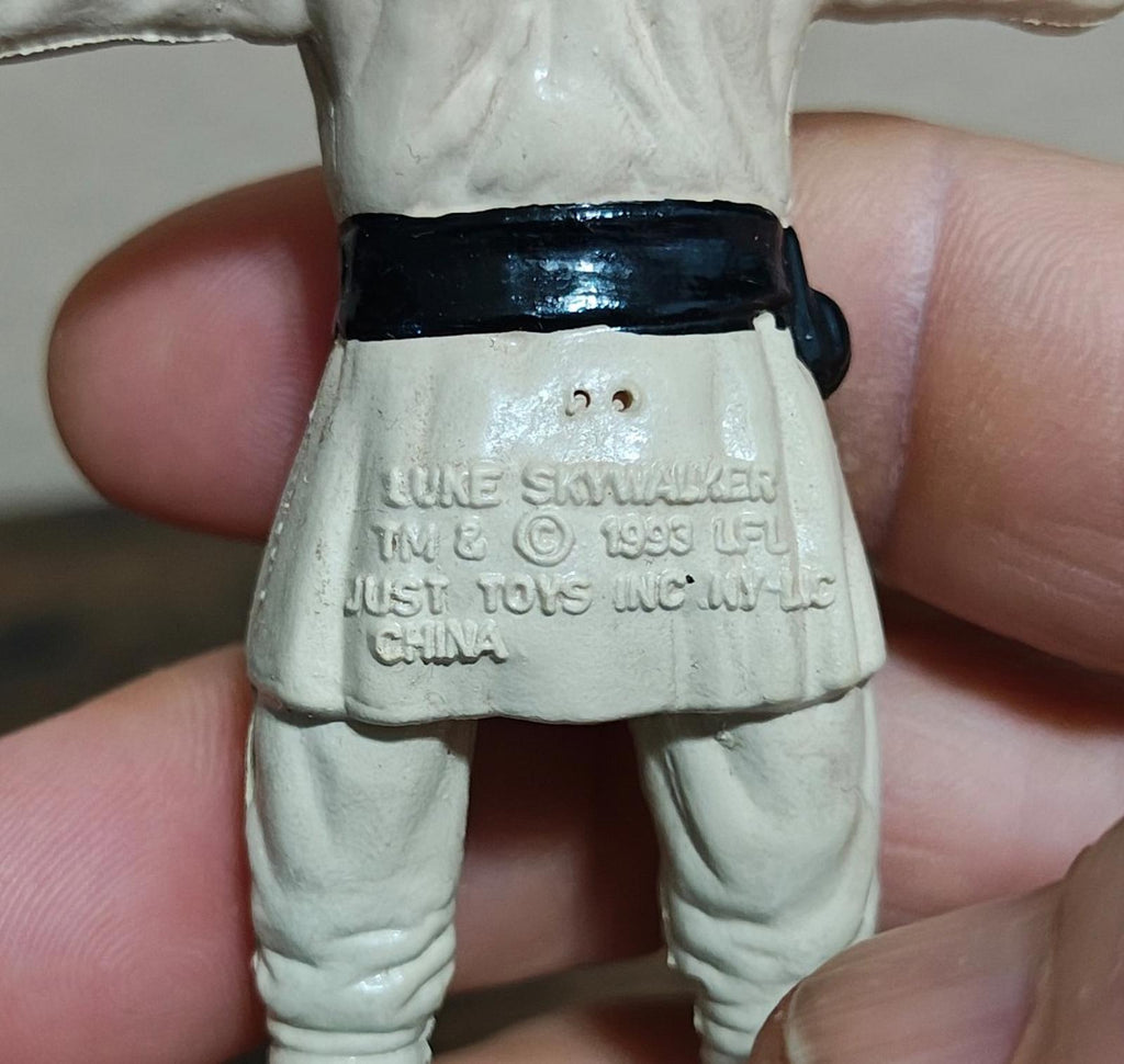 Luke Skywalker figure belt with stamped text, close-up, cream pants and black waistband