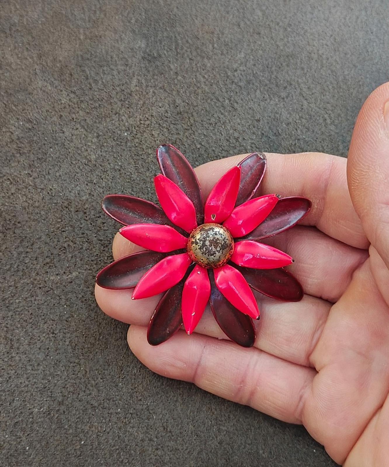 Red and burgundy daisy enamel pin brooch in hand, glossy petal details