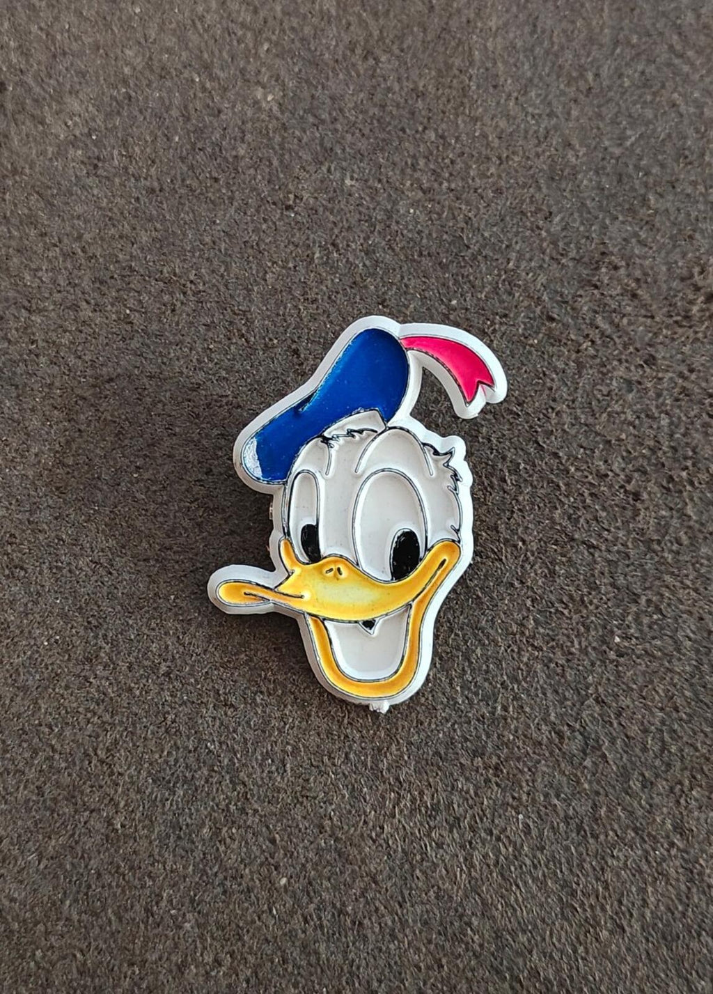 Vintage Donald Duck plastic pin, centered front view with blue cap and yellow beak