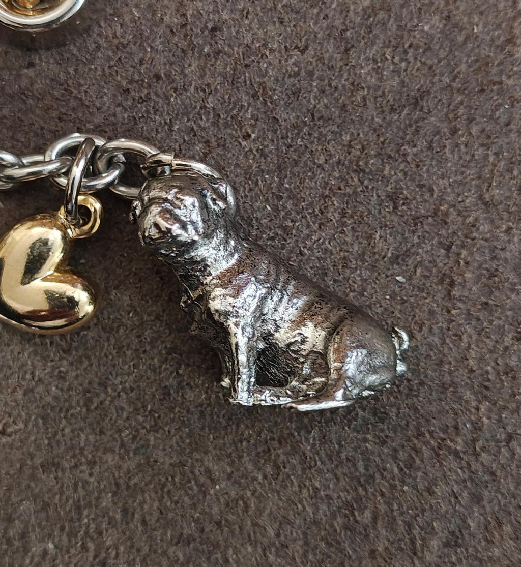 Close-up of metal dog charm on a dog-themed keyring with gold heart and chain links