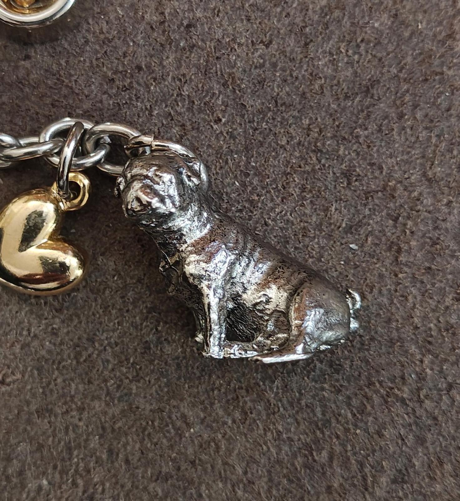 Close-up of metal dog charm on a dog-themed keyring with gold heart and chain links