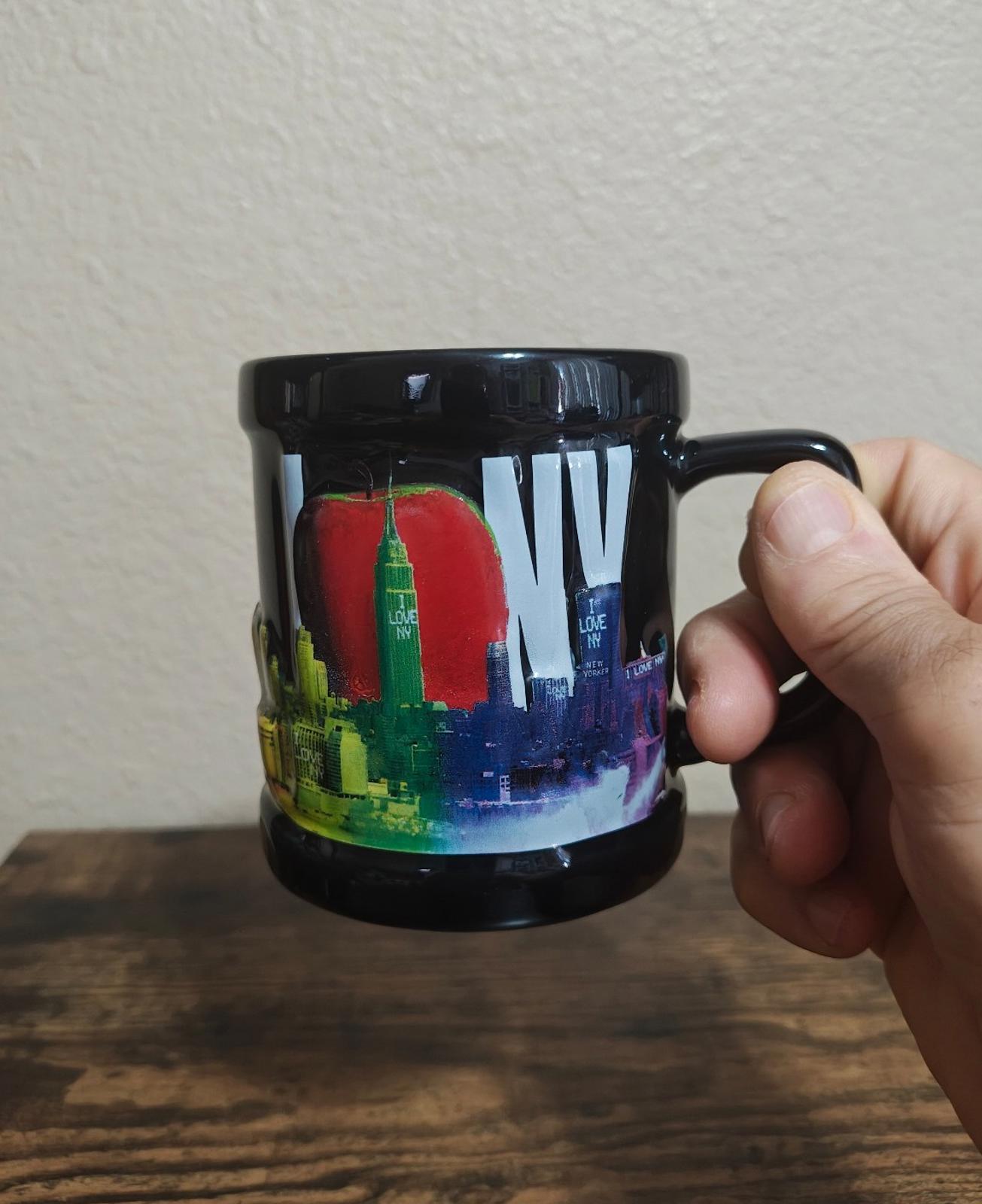 Black ceramic mug with colorful skyline graphic, rounded handle, and glossy finish