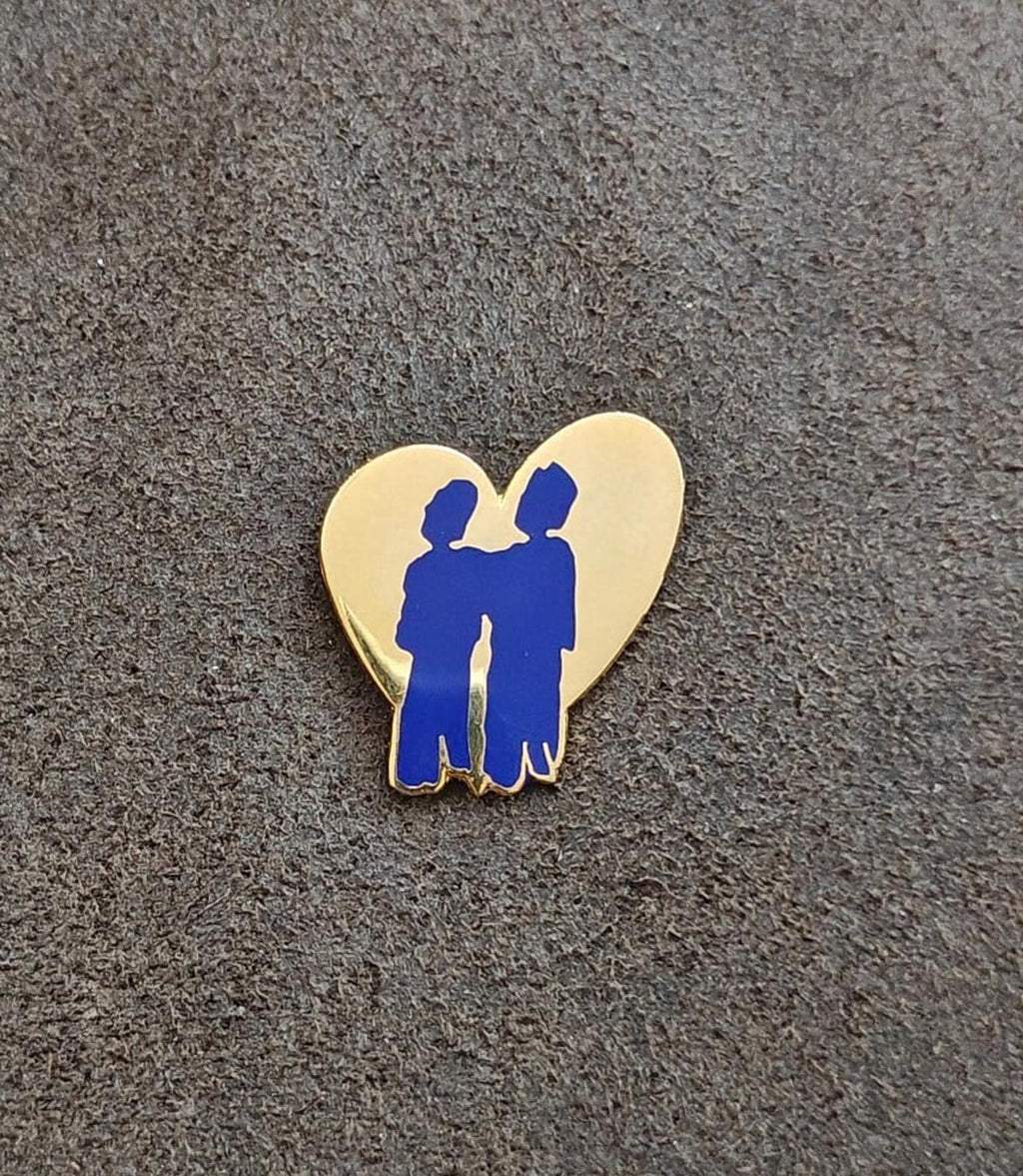 Heart-shaped enamel pin with blue two-friends silhouettes, gold-tone outline