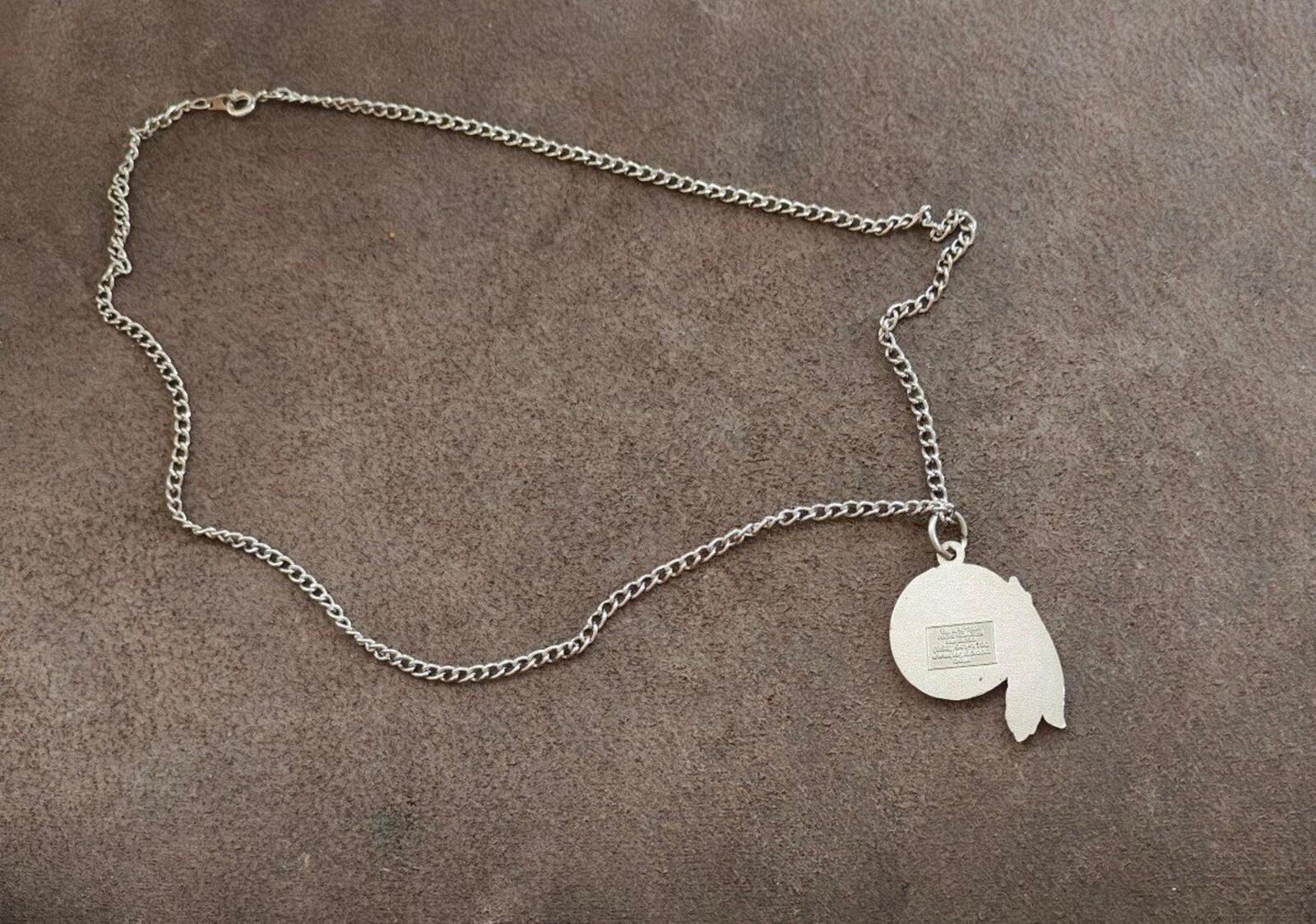 Silver necklace chain with round team logo pendant and small feather tag