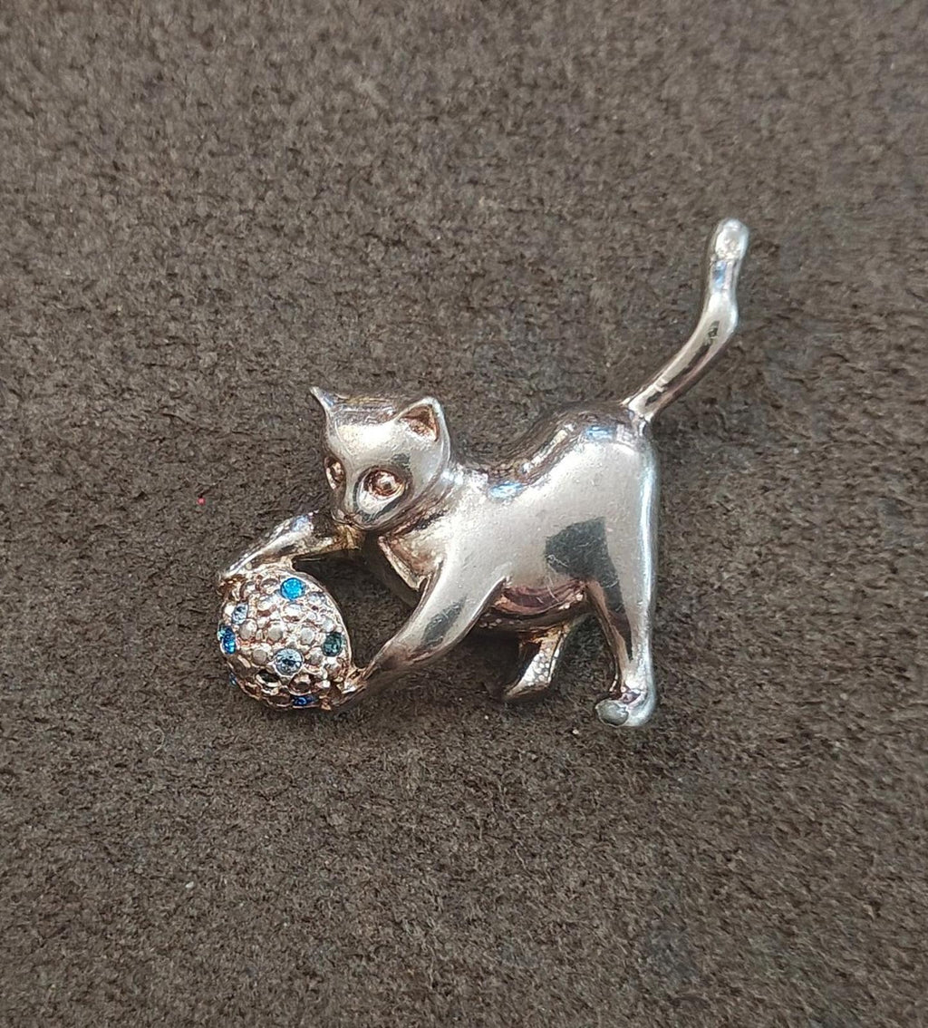 Silver-tone cat brooch with textured blue-stone ball, side view