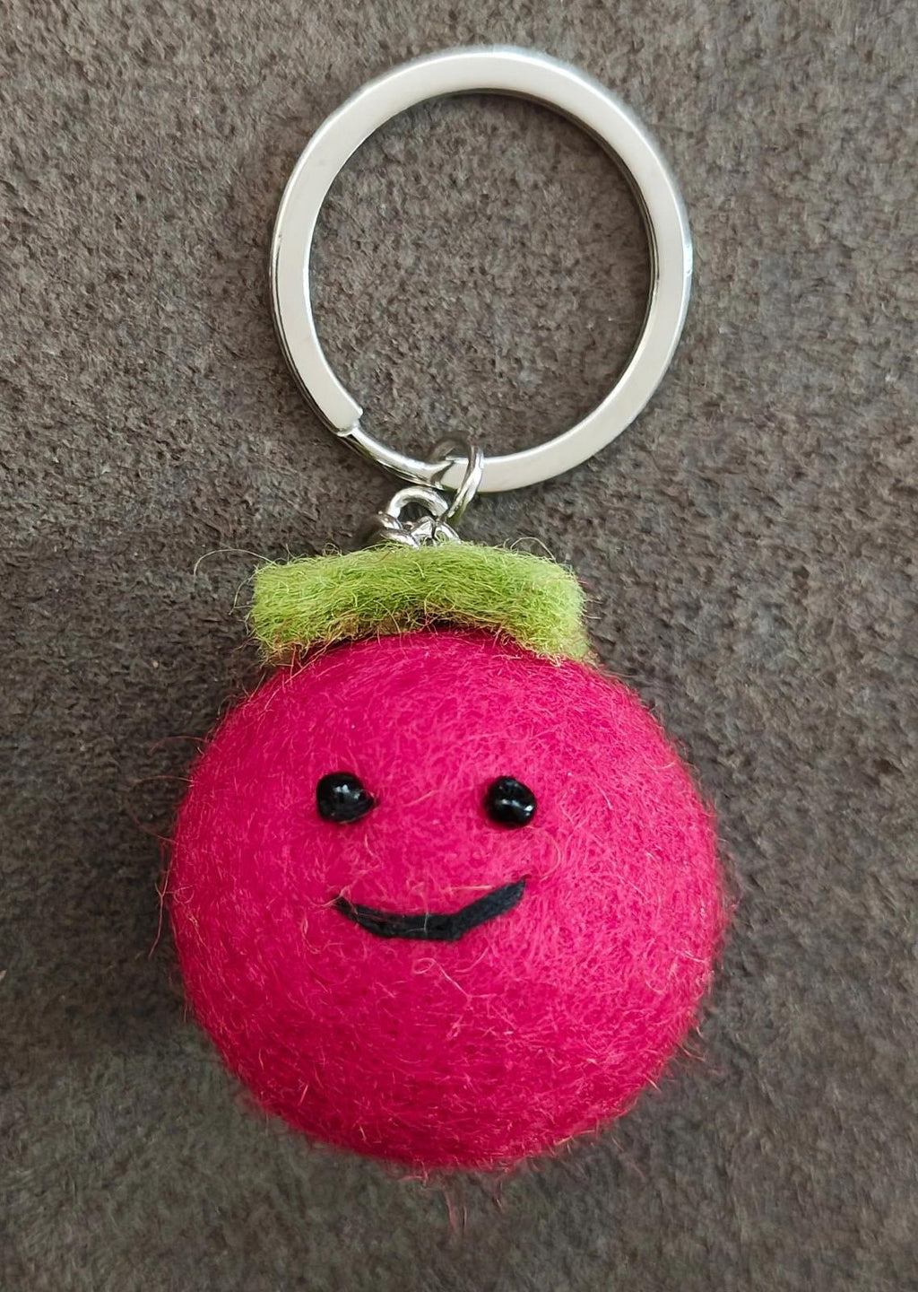 Red felt tomato keychain with green cap, embroidered eyes, smile, and silver ring